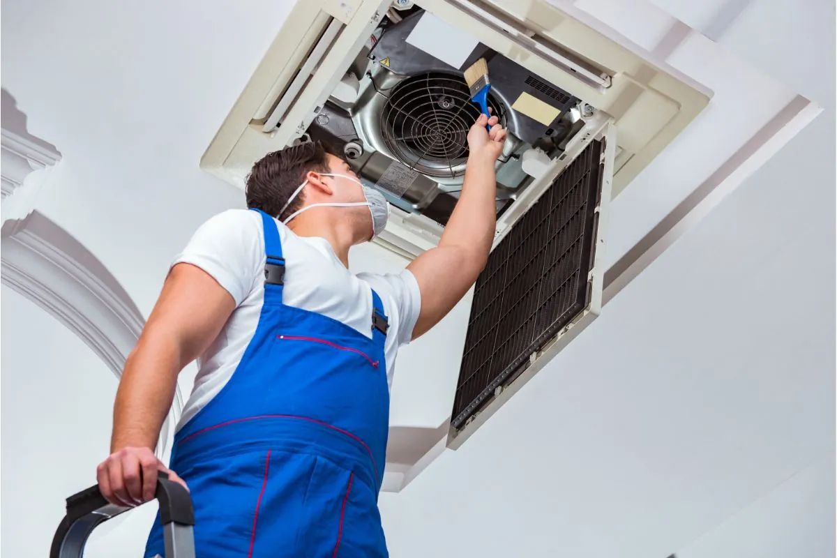 worker cleaning ceiling air conditioning unit