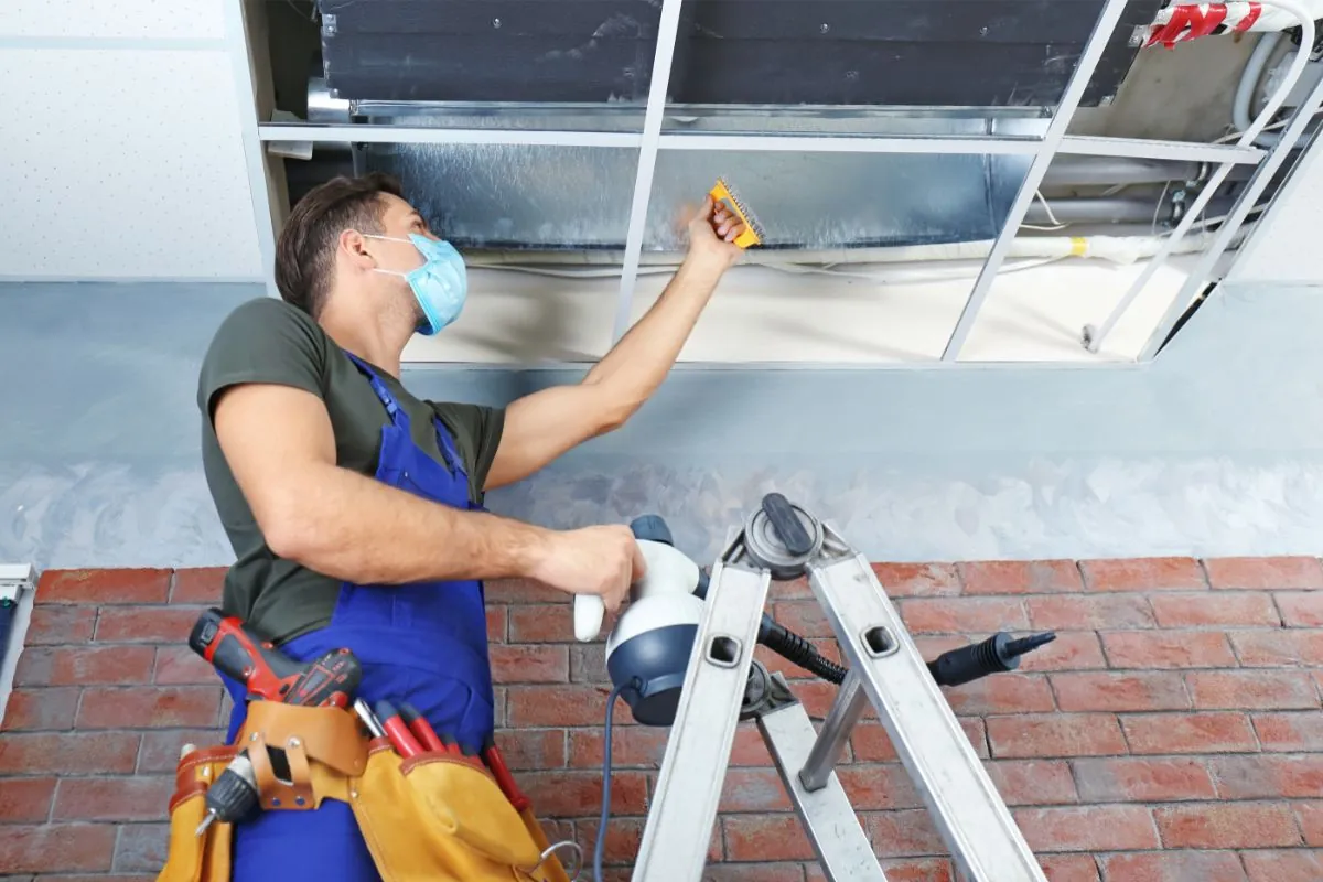 male technician cleaning commercial vent