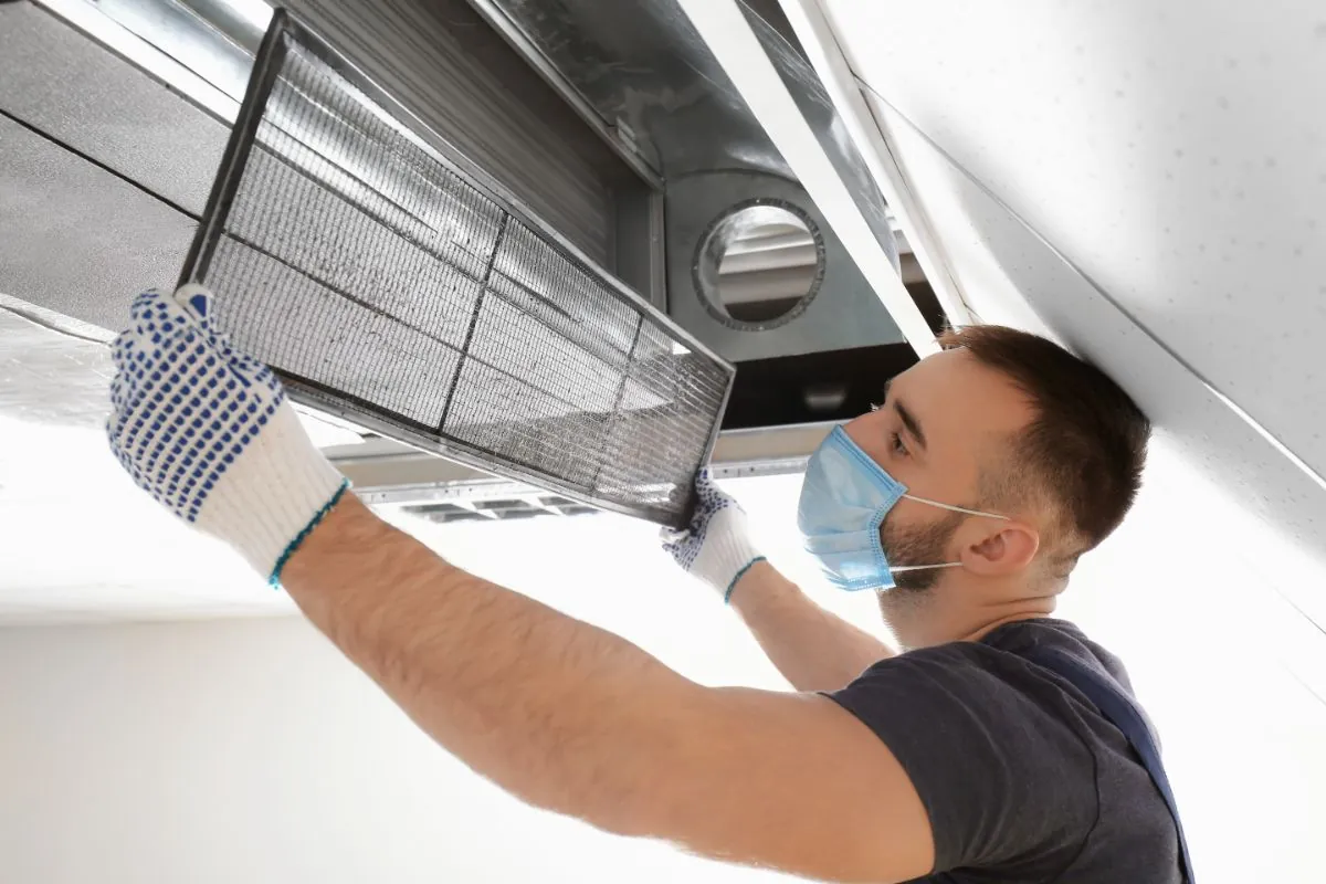 technician taking down air duct filter for cleaning