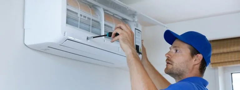 hvac services technician installing air conditioner on the wall at home