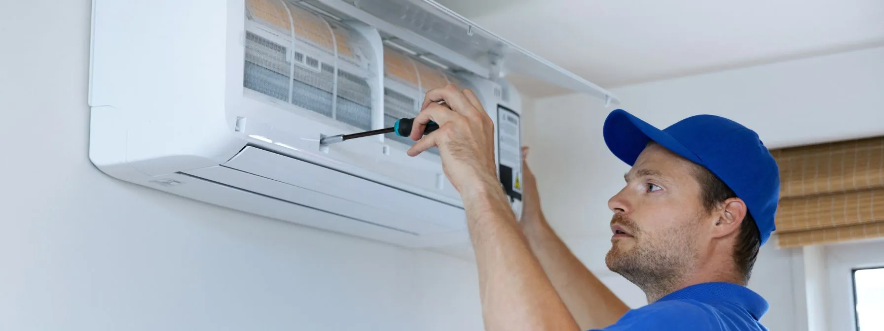 hvac services technician installing air conditioner on the wall at home