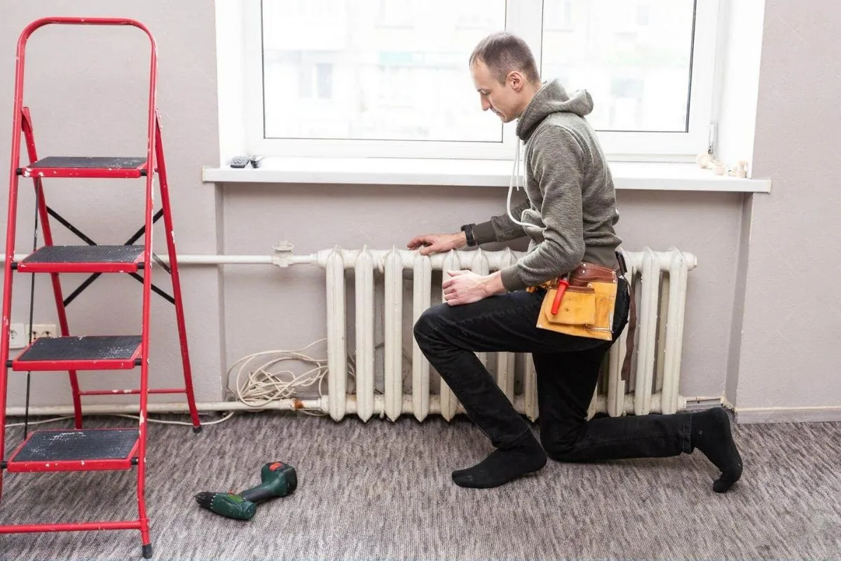 man repairing heating radiator