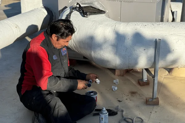 man repairing ac in commercial building rooftop