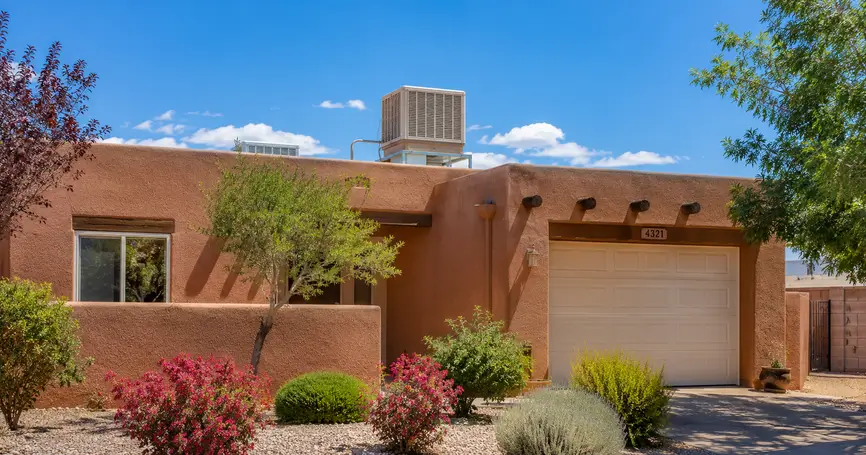 Albuquerque stucco home with a rooftop swamp cooler, desert landscaping, and bright summer sunshine under a clear blue New Mexico sky.